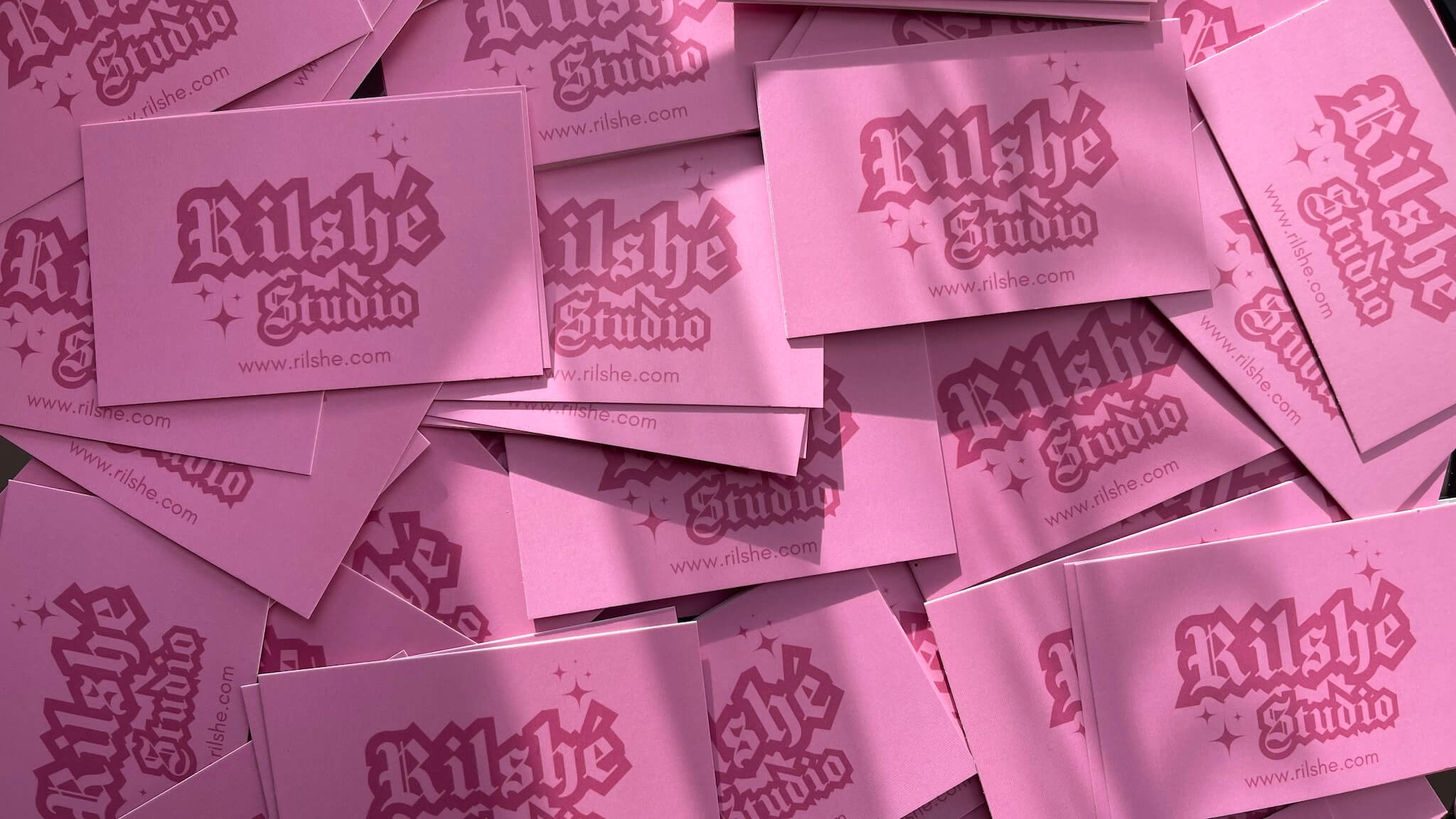 Plusieurs cartes de visite roses de Rilshé disposées en tas